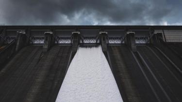 A dam in black and white with water coming down one area