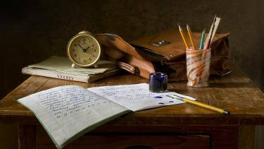 Early Dismissal Day A school desk with a clock, papers, pens and pencils on it