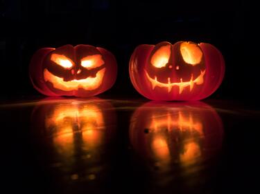 Two pumpkins lit up in the darkness