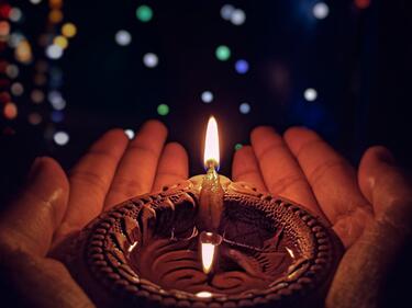 Hands cupping a lit candle